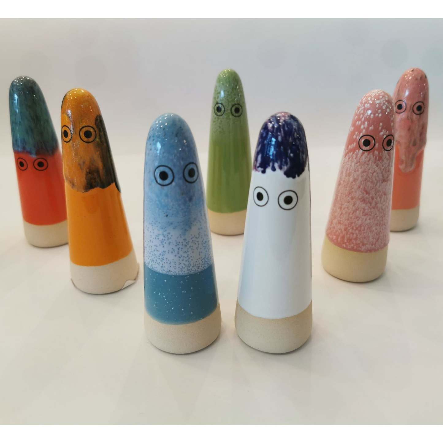 A group of 7 cone-shaped ceramic figurines with hand-painted eyes