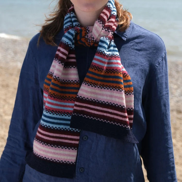 Woman wearing a colourful striped scarf on a beach