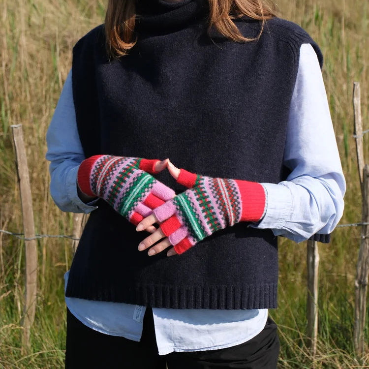 Woman wearing a dark vest and colourful knitted gloves in a field