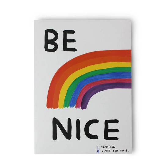 A rectangular tea towel with David Shirgley's "Be Nice" artwork of a rainbow.