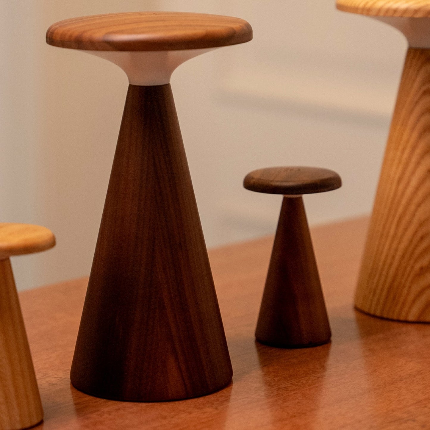 Wooden lights of various sizes with a cone-shaped design on a wooden surface