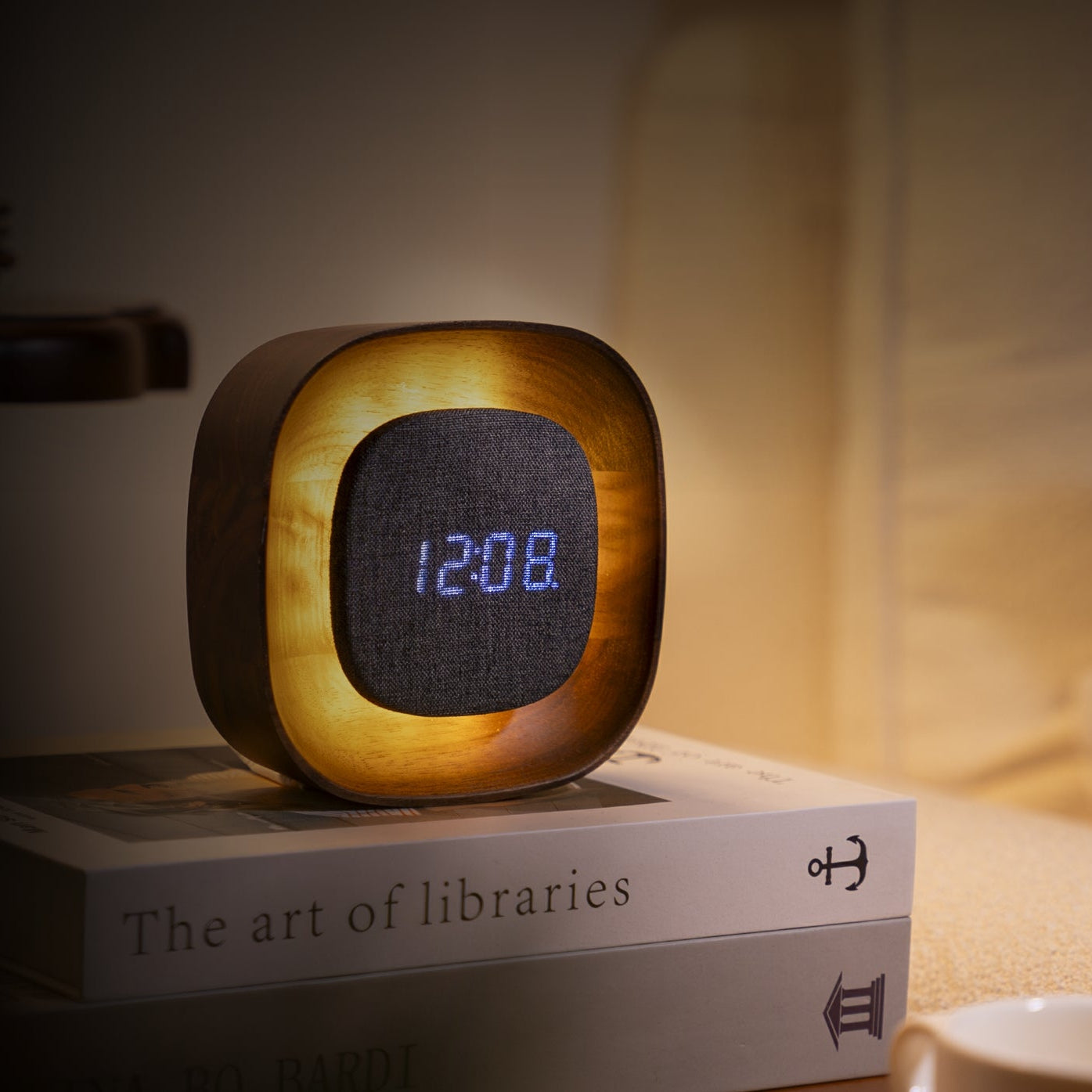 Digital clock light with wooden frame on a book titled 'The art of libraries'