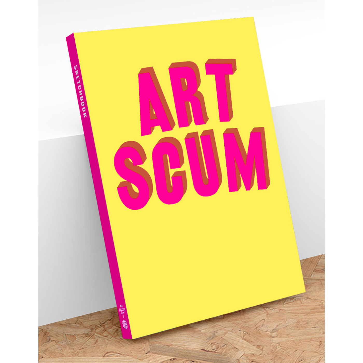 A sketchbook with a yellow cover featuring the text 'ART SCUM' in bold pink letters.