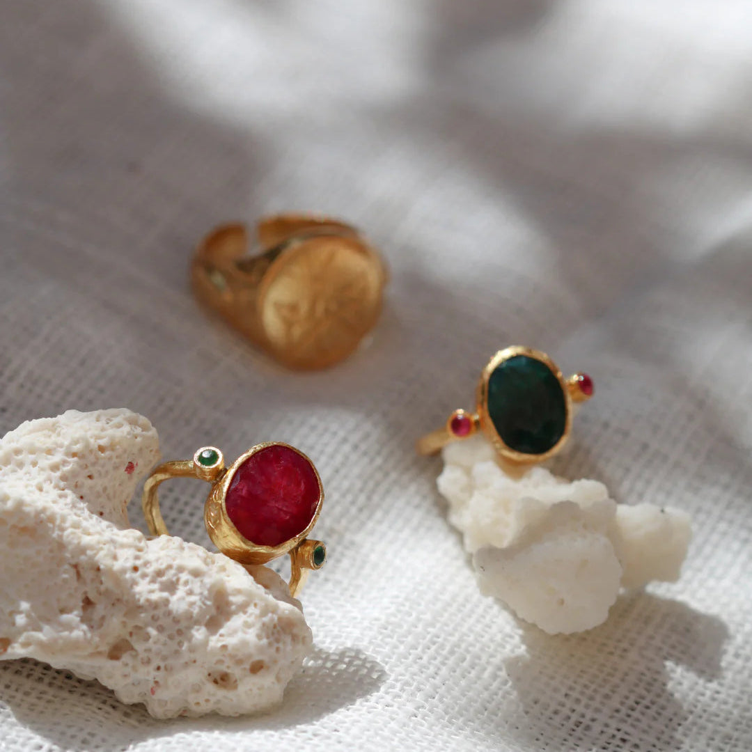 Gold rings with gemstones on a textured white surface