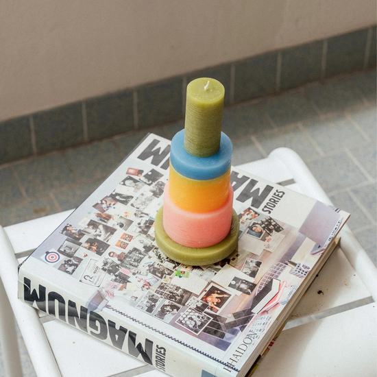  candle made up of 6 different colour components, sitting on a book.