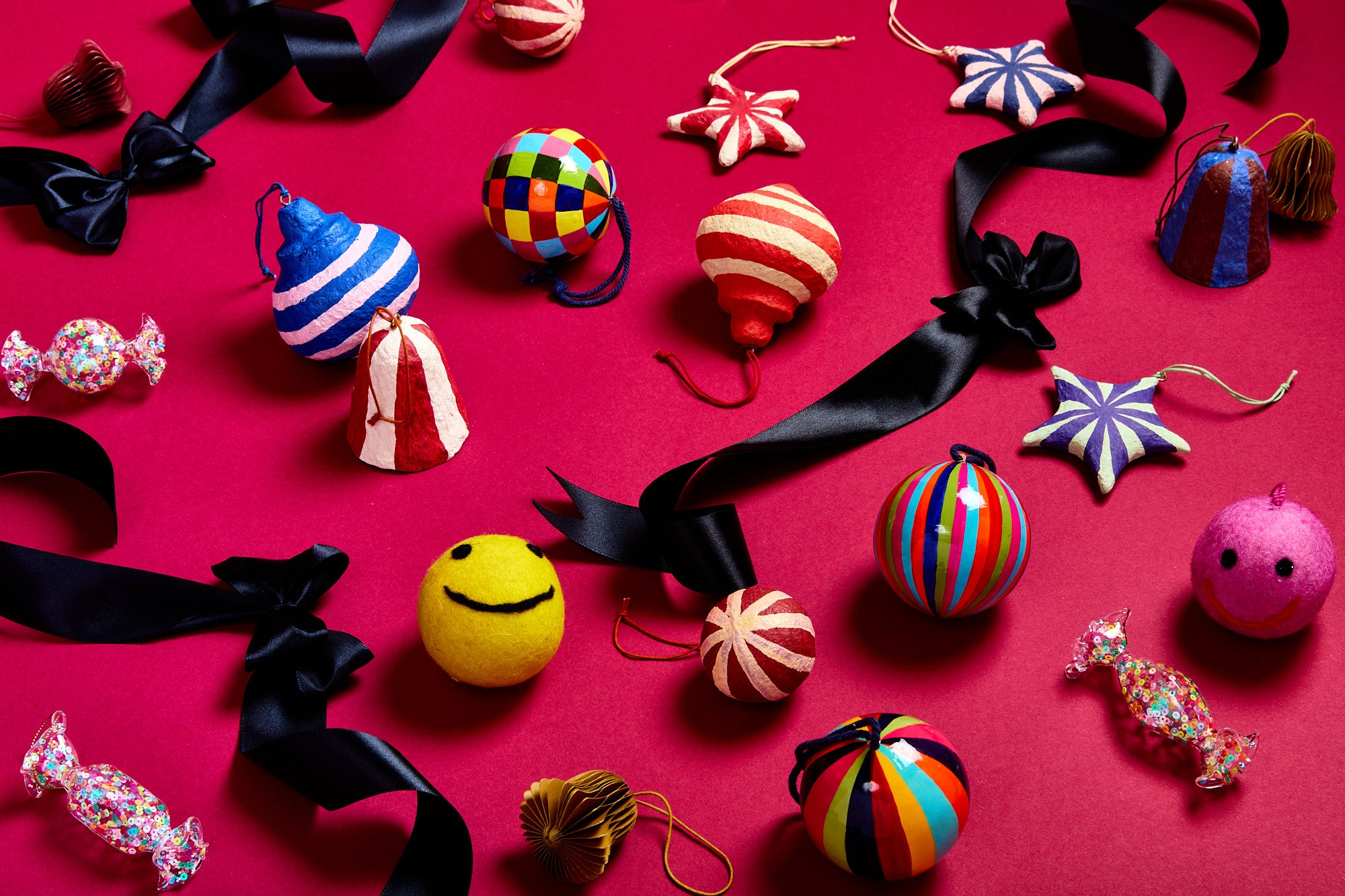 Colourful Christmas tree decorations and black ribbons on a red background