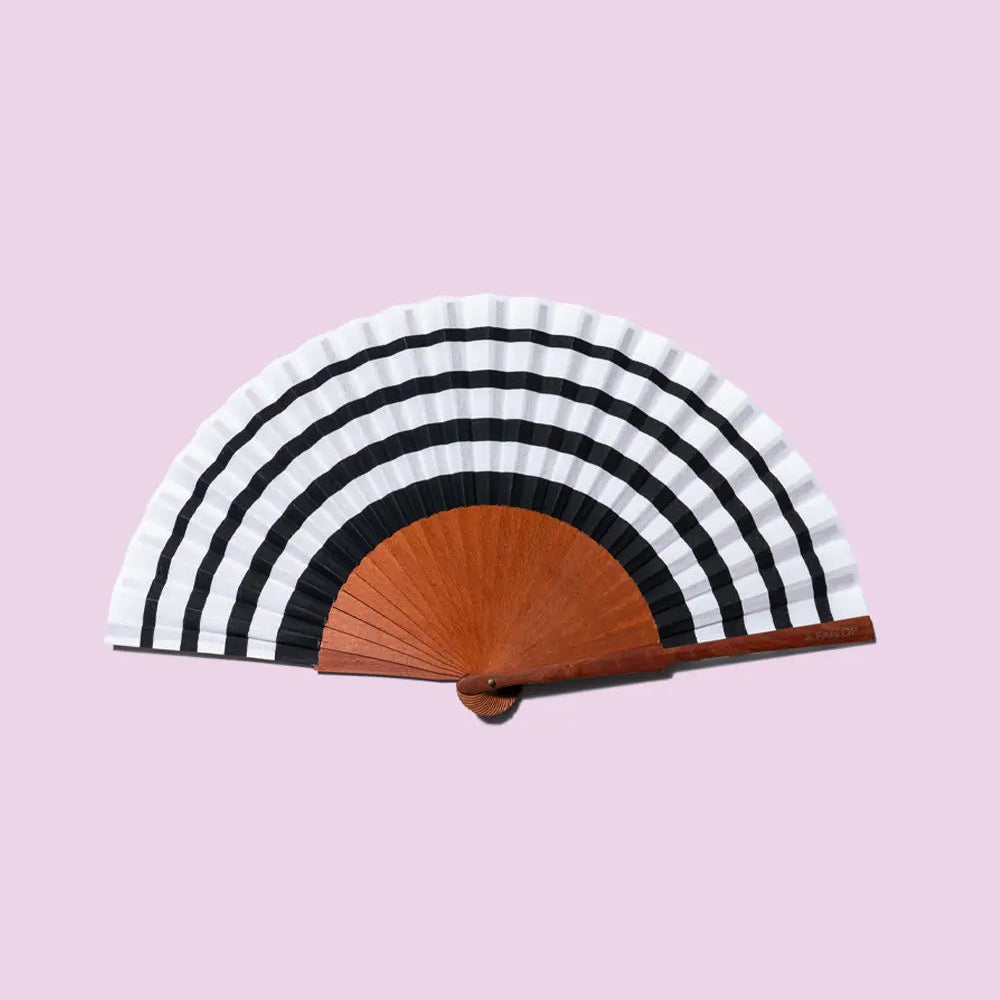 Striped hand fan with wooden handle on a pink background