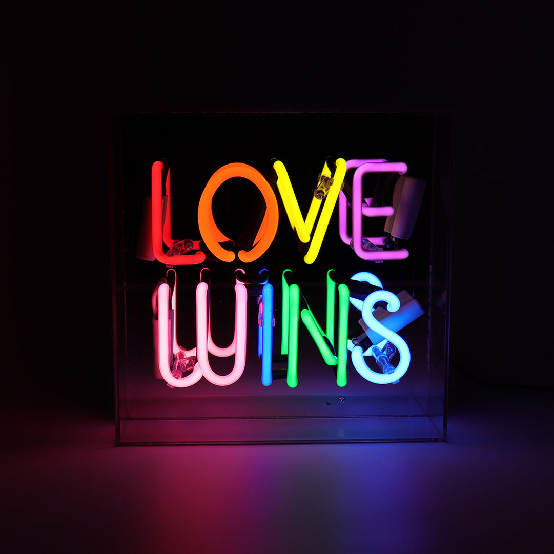 Neon sign with the words 'LOVE WINS' on a black background