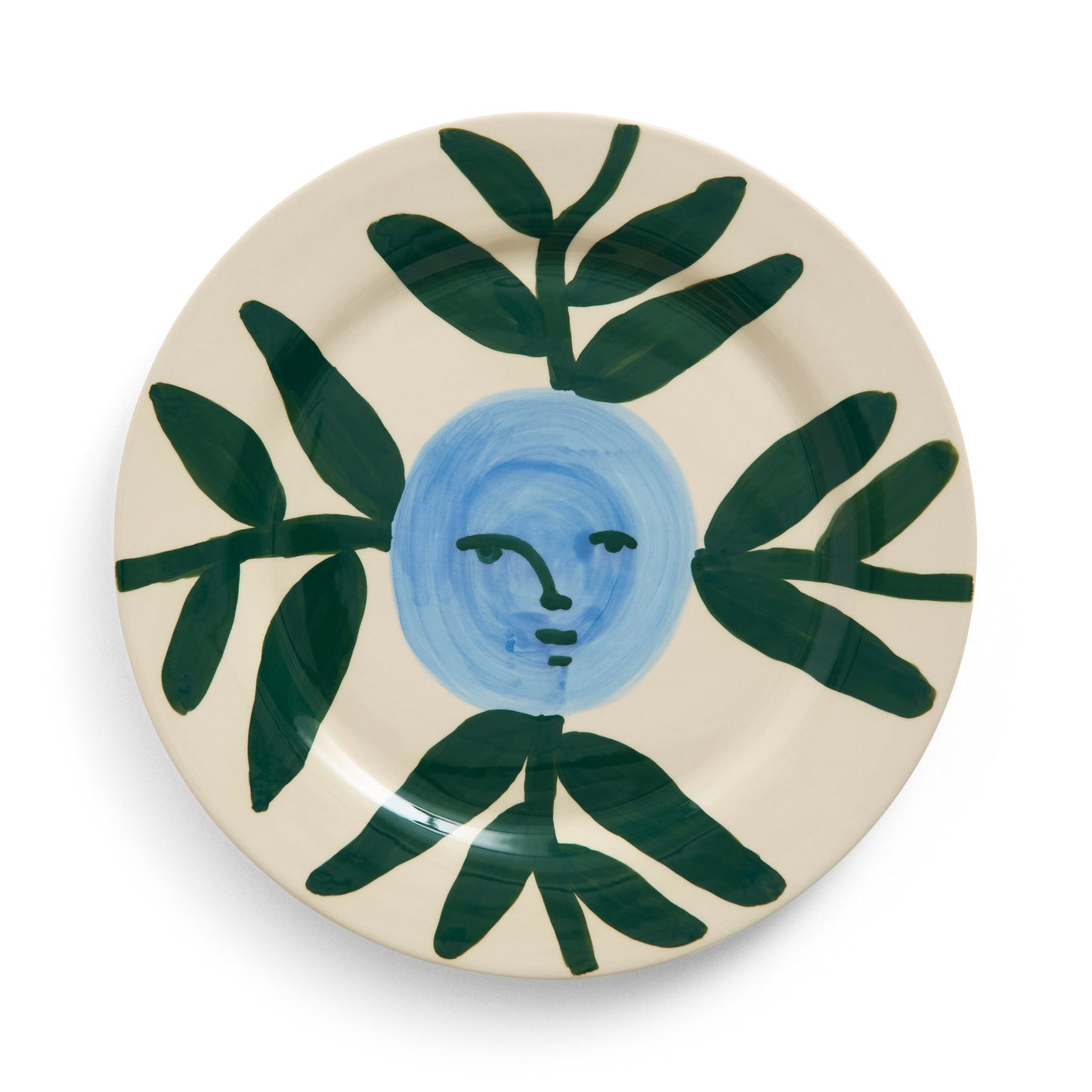 Ceramic plate with blue face and green leaves on a white background