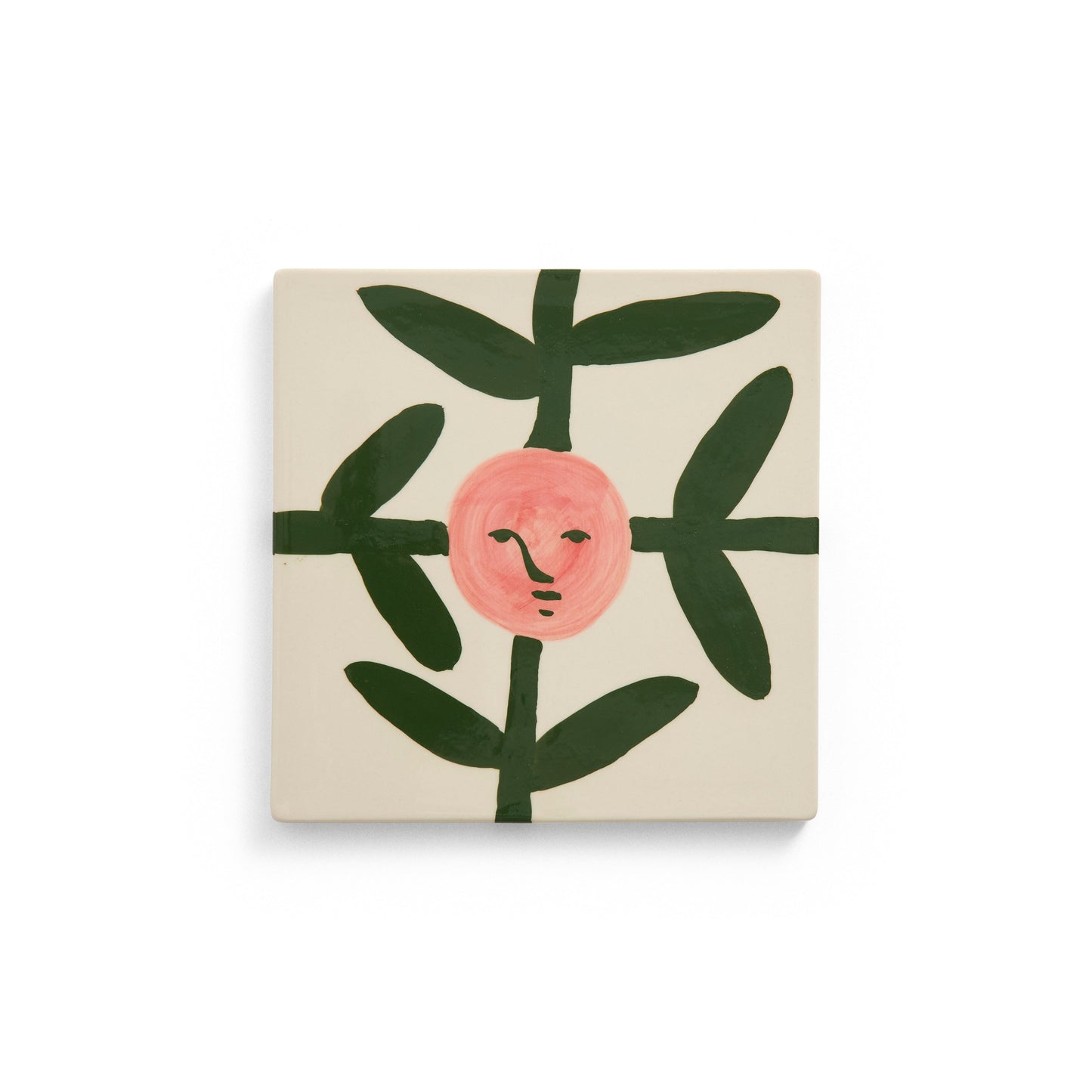 Square tile with a pink face surrounded by green leaves on a beige background