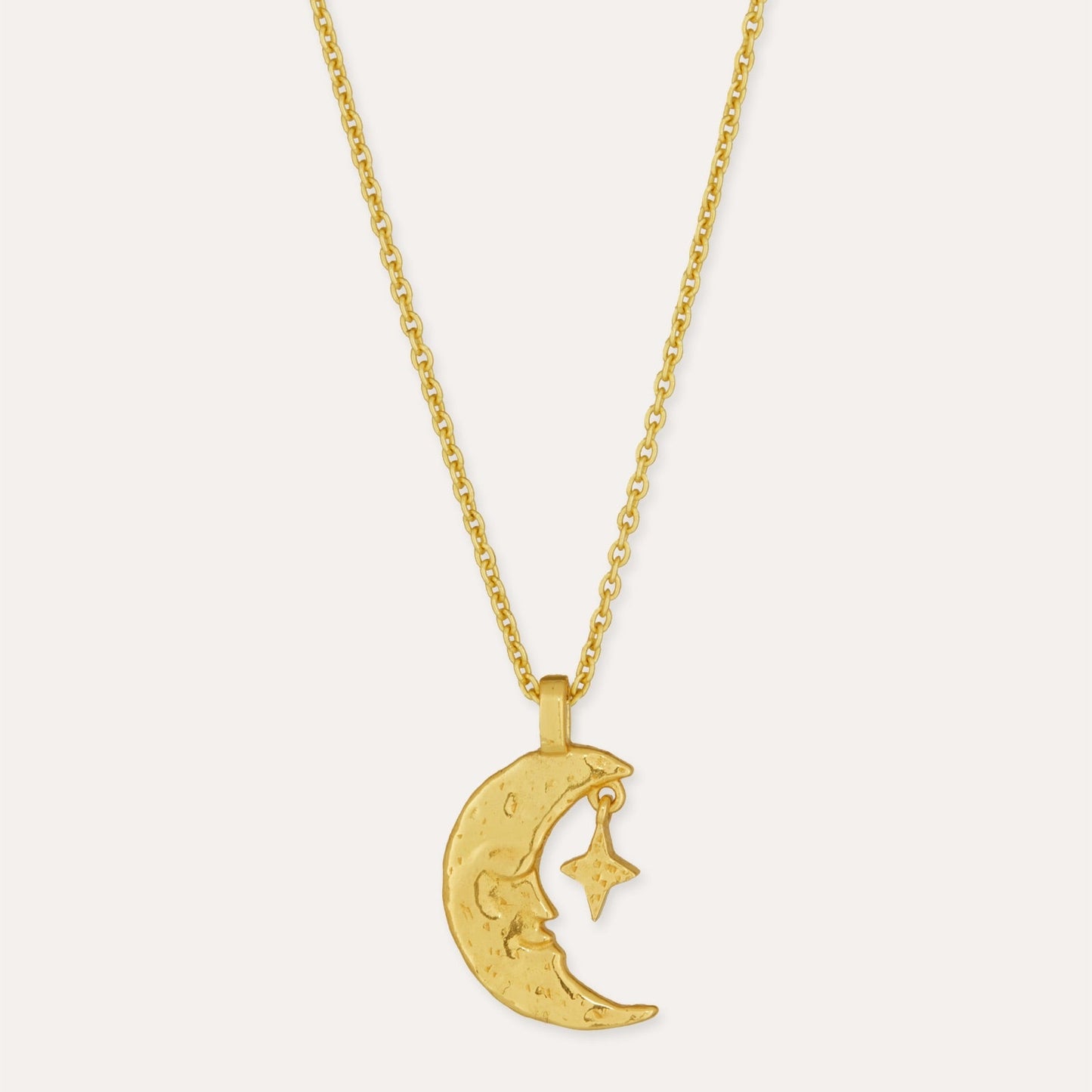 Gold necklace with a crescent moon pendant on a light gray background
