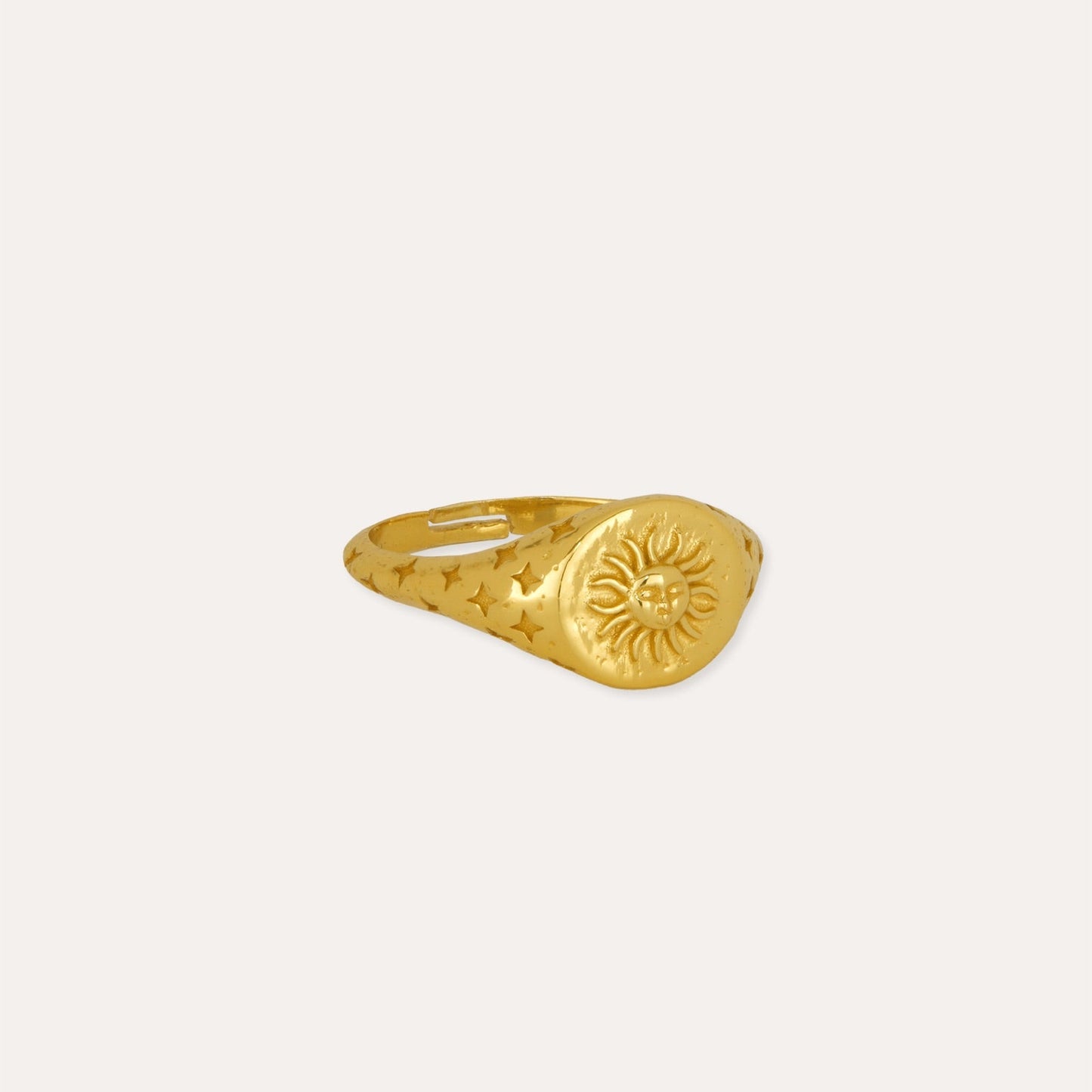 Gold ring with sun design on a white background