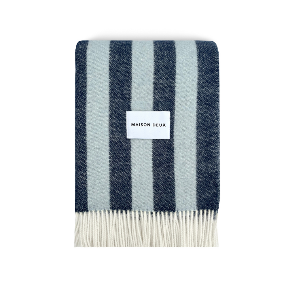 
                  
                    Folded wool striped design blanket, with frilly edges and brand label in the centre.
                  
                