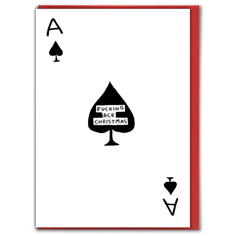 A greeting card with a David Shrigley illustration of the Ace of Spades playing card, featuring black spade symbols and the text 'FUCKING ACE CHRISTMAS' in the centre, with a red envelope visible behind it.