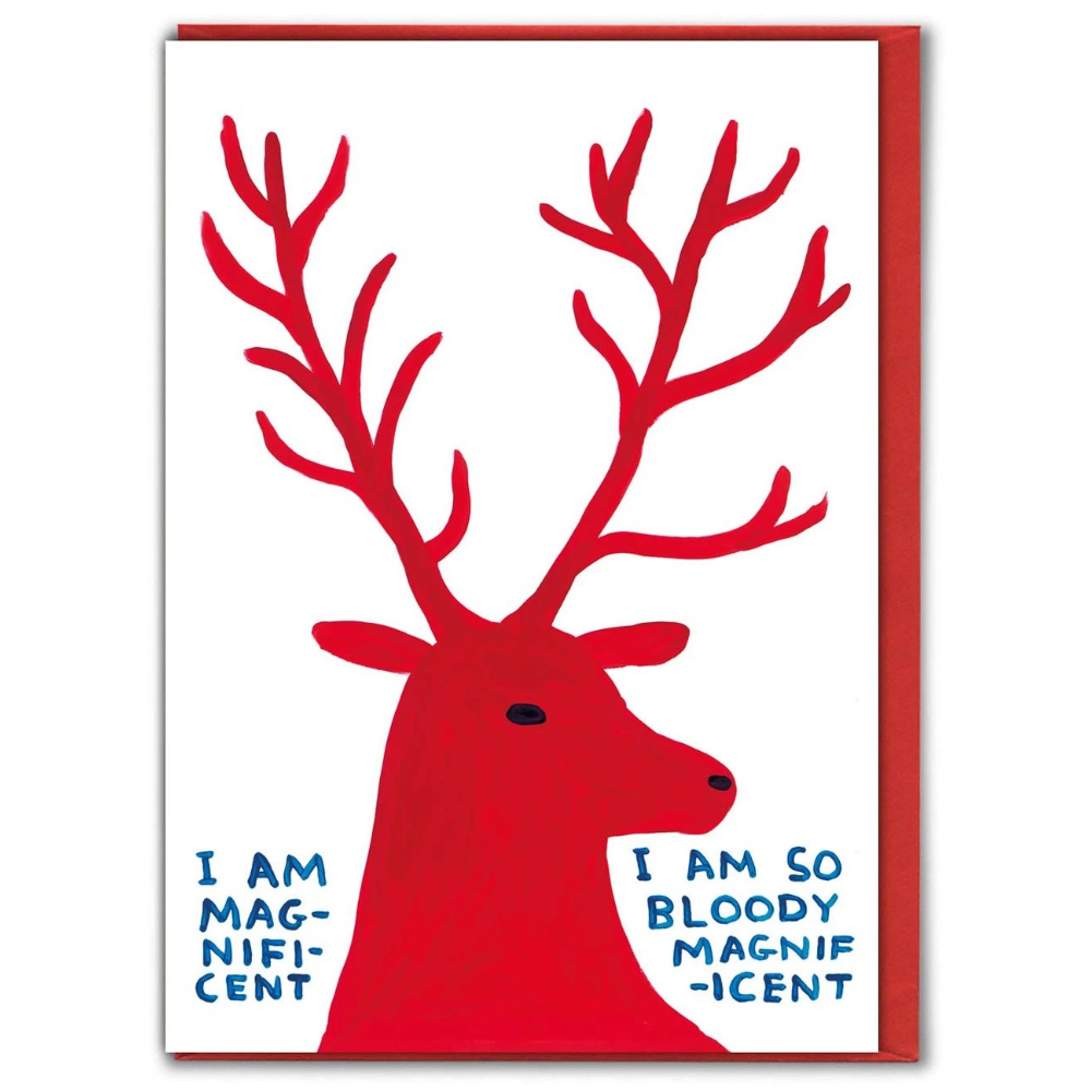 A greeting card featuring a David Shrigley illustration of a bold red stag with blue text reading 'I AM MAGNIFIC-CENT' and 'I AM SO BLOODY MAGNIFIC-CENT', shown with a red envelope against a white background.