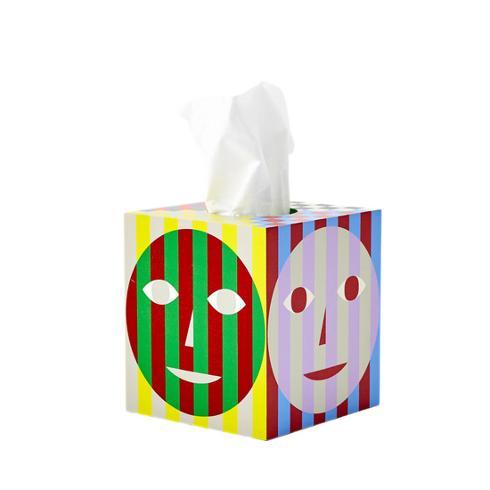A cube shaped tissue box with tissues coming out of the top, colourful stripes and faces design on each side.