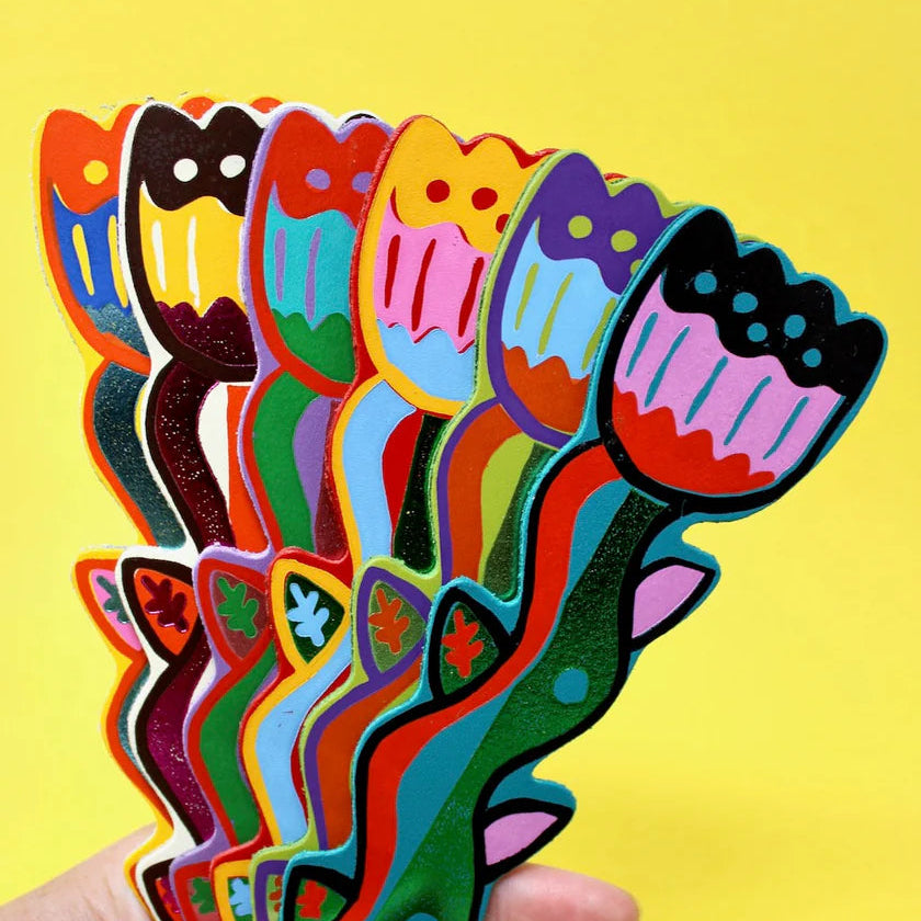 Colorful tulip-shaped leather bookmarks held against a yellow background