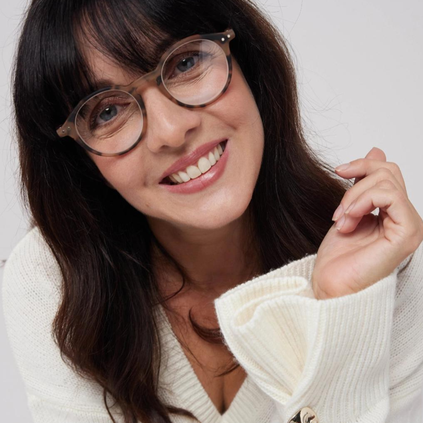 A female with brunette hair smiling, she is wearing the IZIPIZI Iconic Reading Glasses in the colour tortoiseshell.