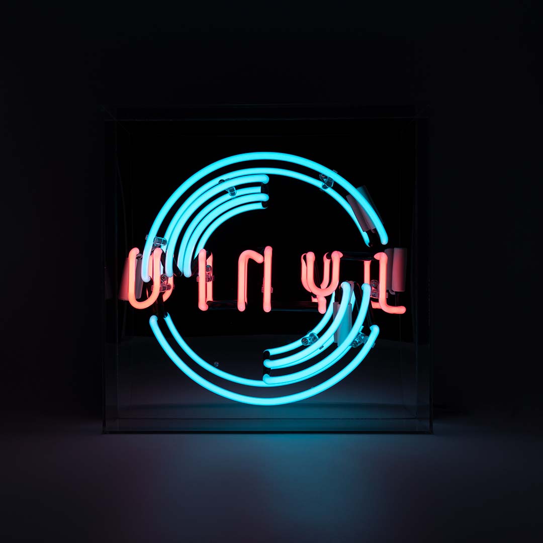 Neon sign with the word 'Vinyl' in pink and blue on a black background