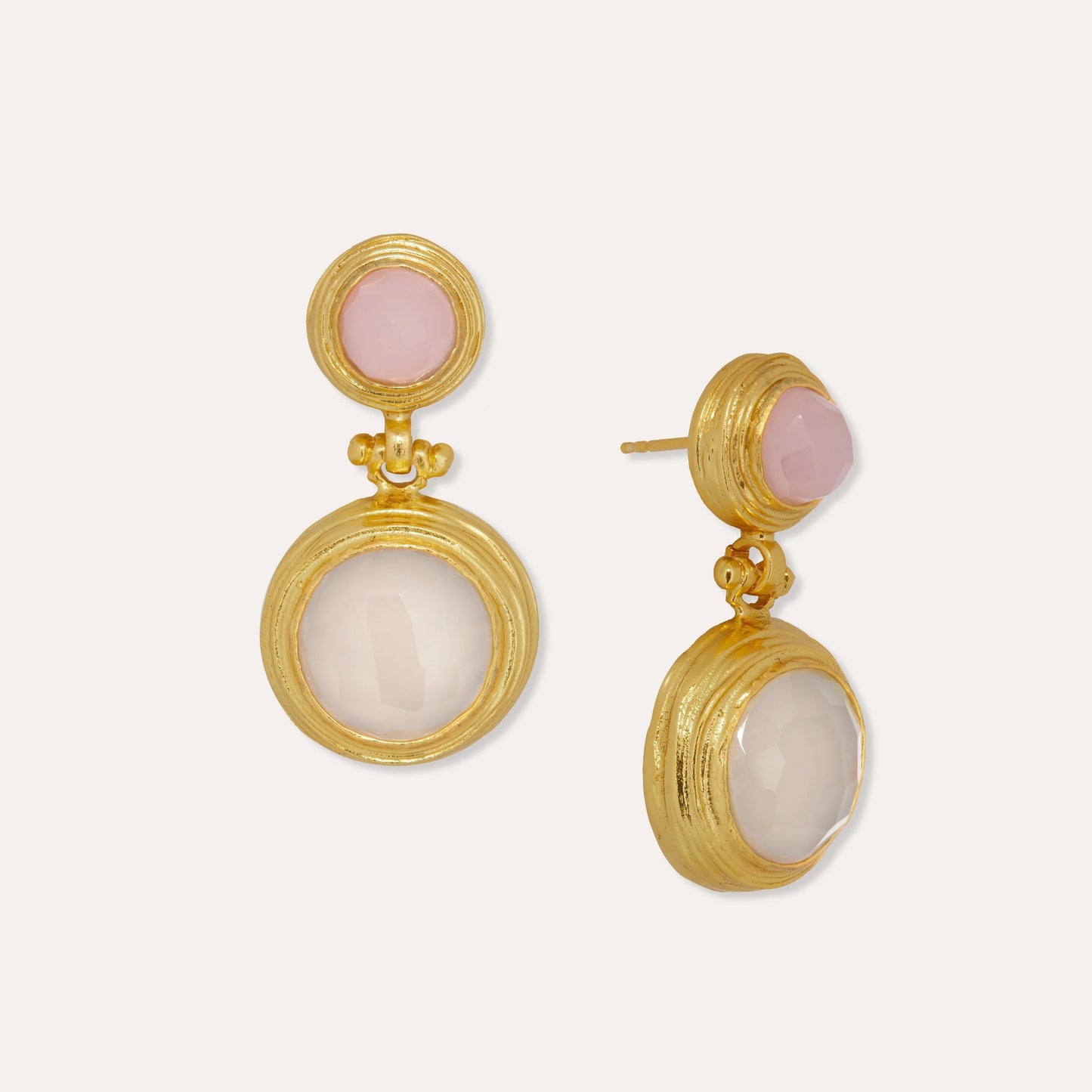 Gold earrings with pink and white stones on a light beige background
