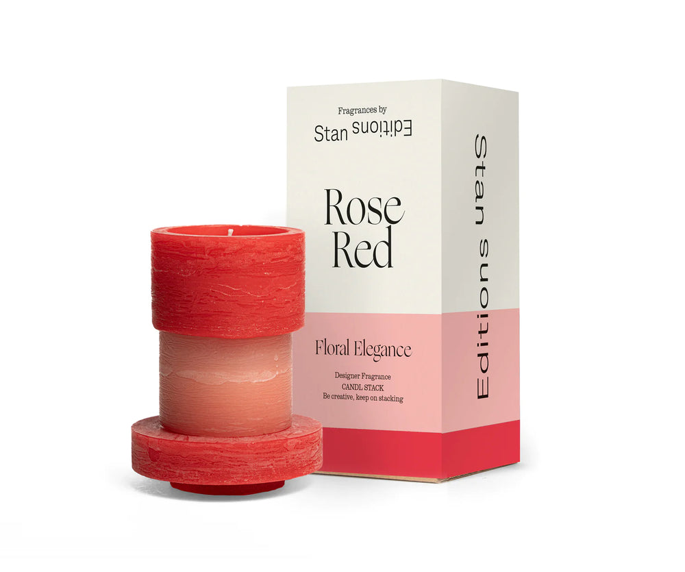 A red and pink 3-layered stacked candle next to box packaging.