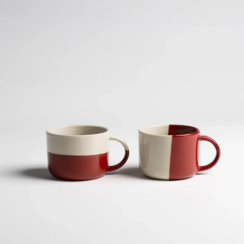 Set of two cream and red mugs. One mug has colours split horizontally, the other mug split vertically.