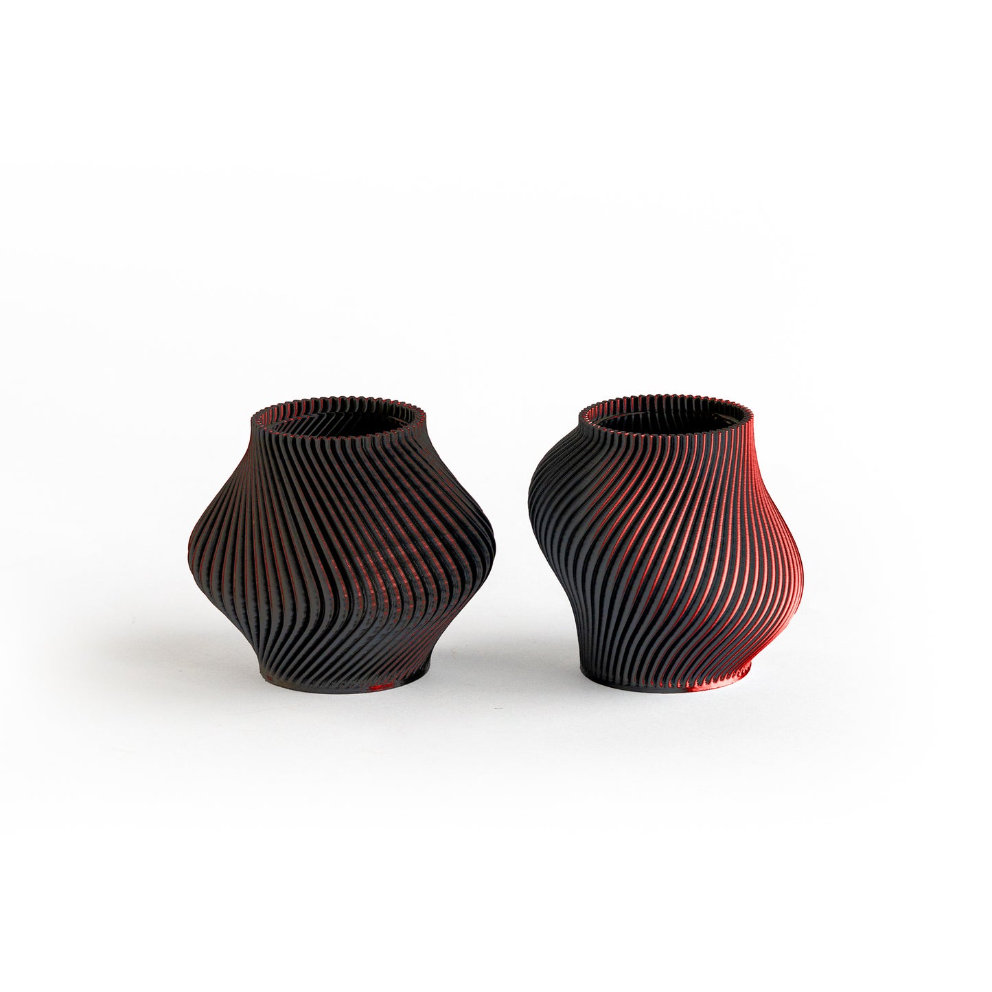 Two black and red textured vases on a white background
