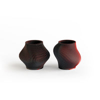 Two black and red textured vases on a white background