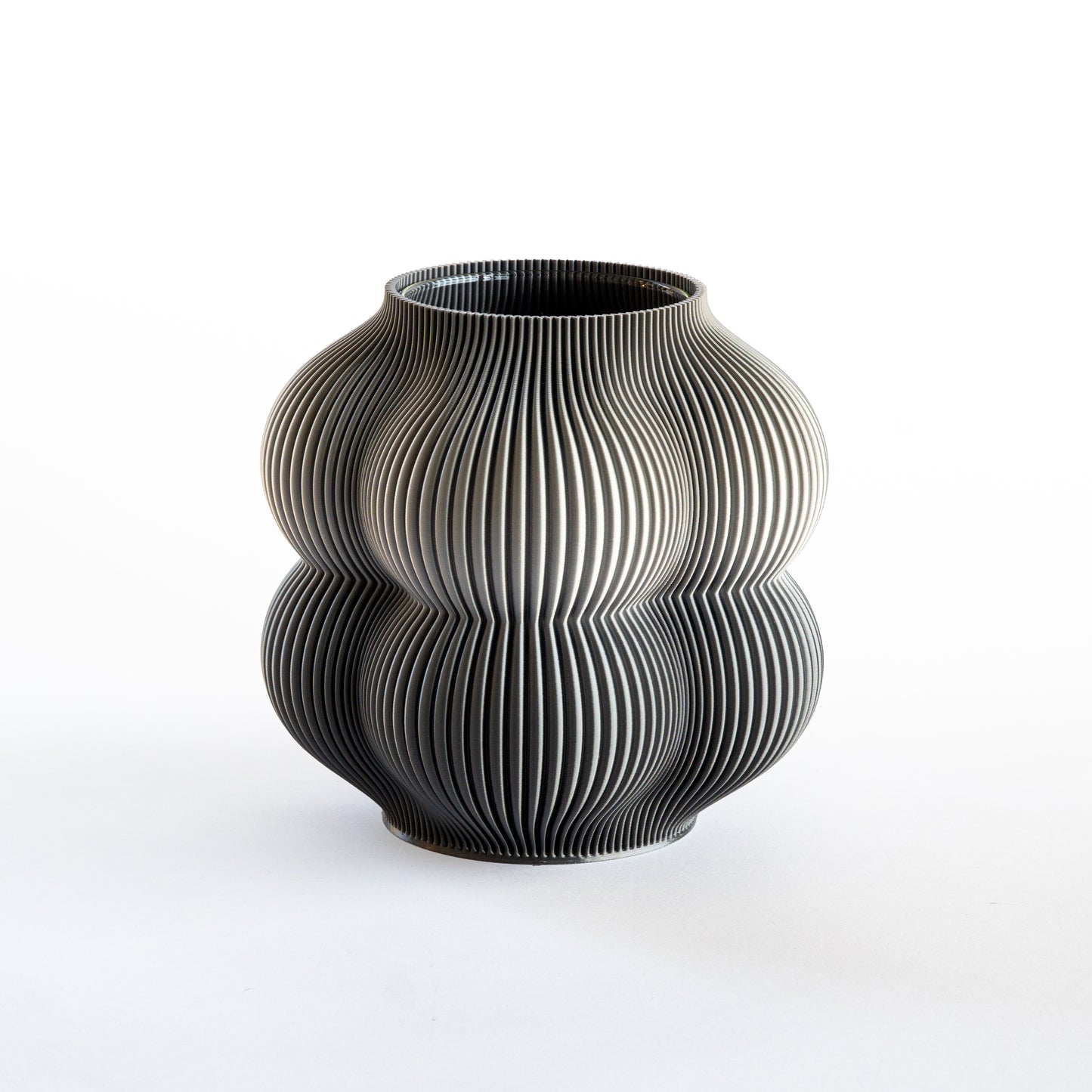 Black ceramic vase with ribbed texture on a white background