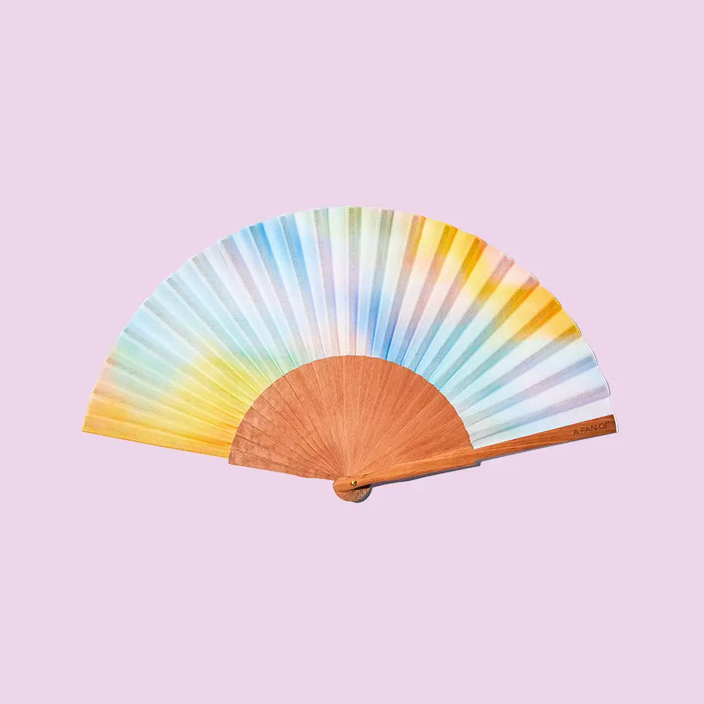 Colorful hand fan with a gradient design on a light purple background