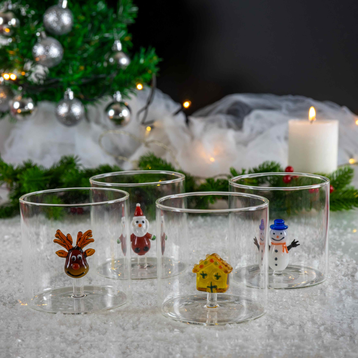 Set of Christmas-themed glass tumblers with figurines on a festive background.