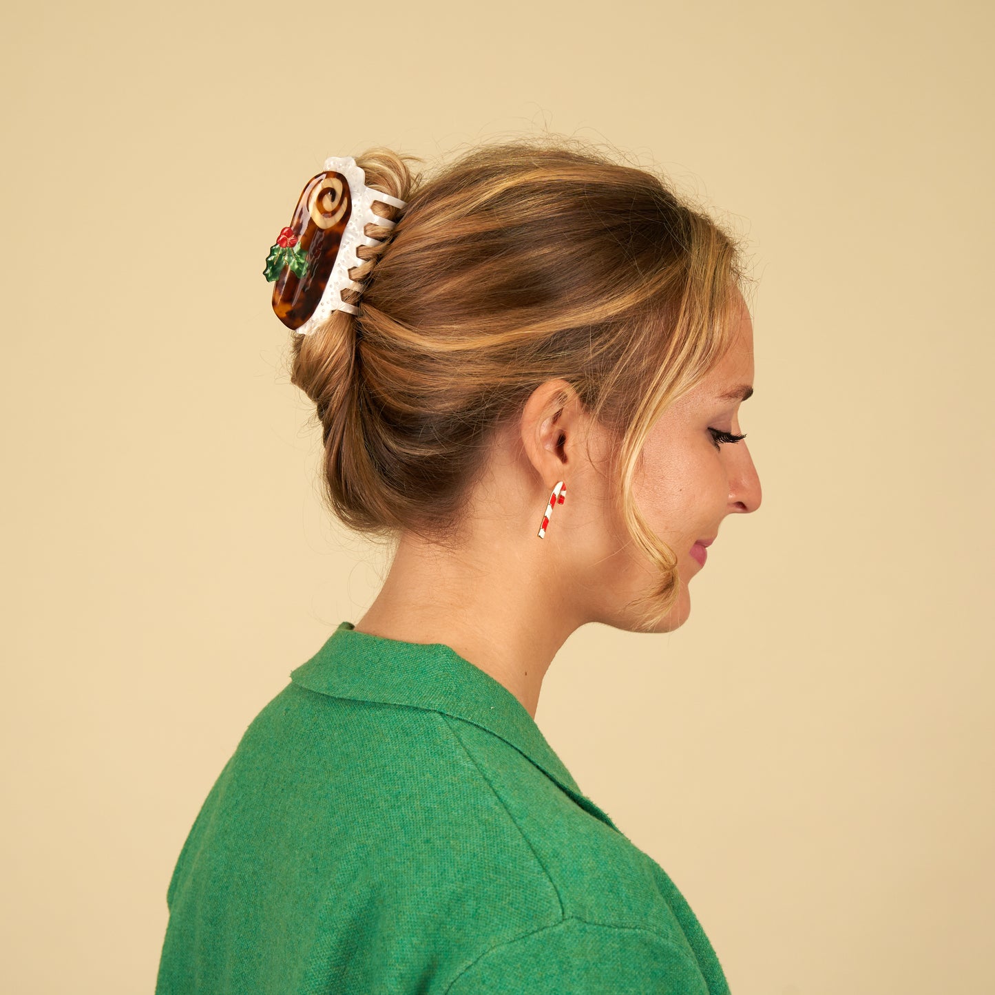 A person with their hair clipped in an up do with a claw clip in the shape of a Christmas Yule Log