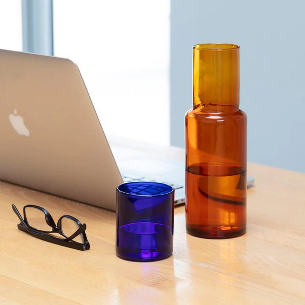 
                      
                        water carafe with glass on desk with pair of glasses.
                      
                    