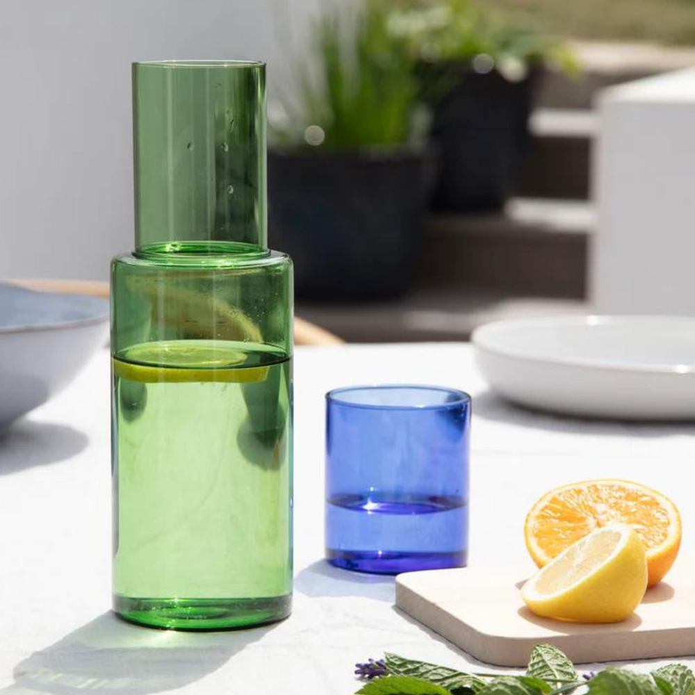 
                      
                        water carafe and glass on table with a lemon.
                      
                    