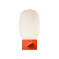 A modern lamp with a rounded, capsule-shaped frosted white glass shade mounted on a square, matte red base with a circular dial, isolated on a solid white background.