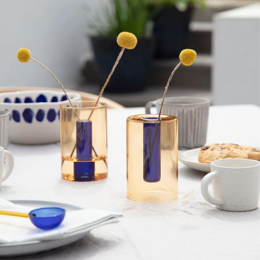 
                      
                        reversible glass vase in cobalt and peach on a table setting with mugs, bowls and spoons.
                      
                    