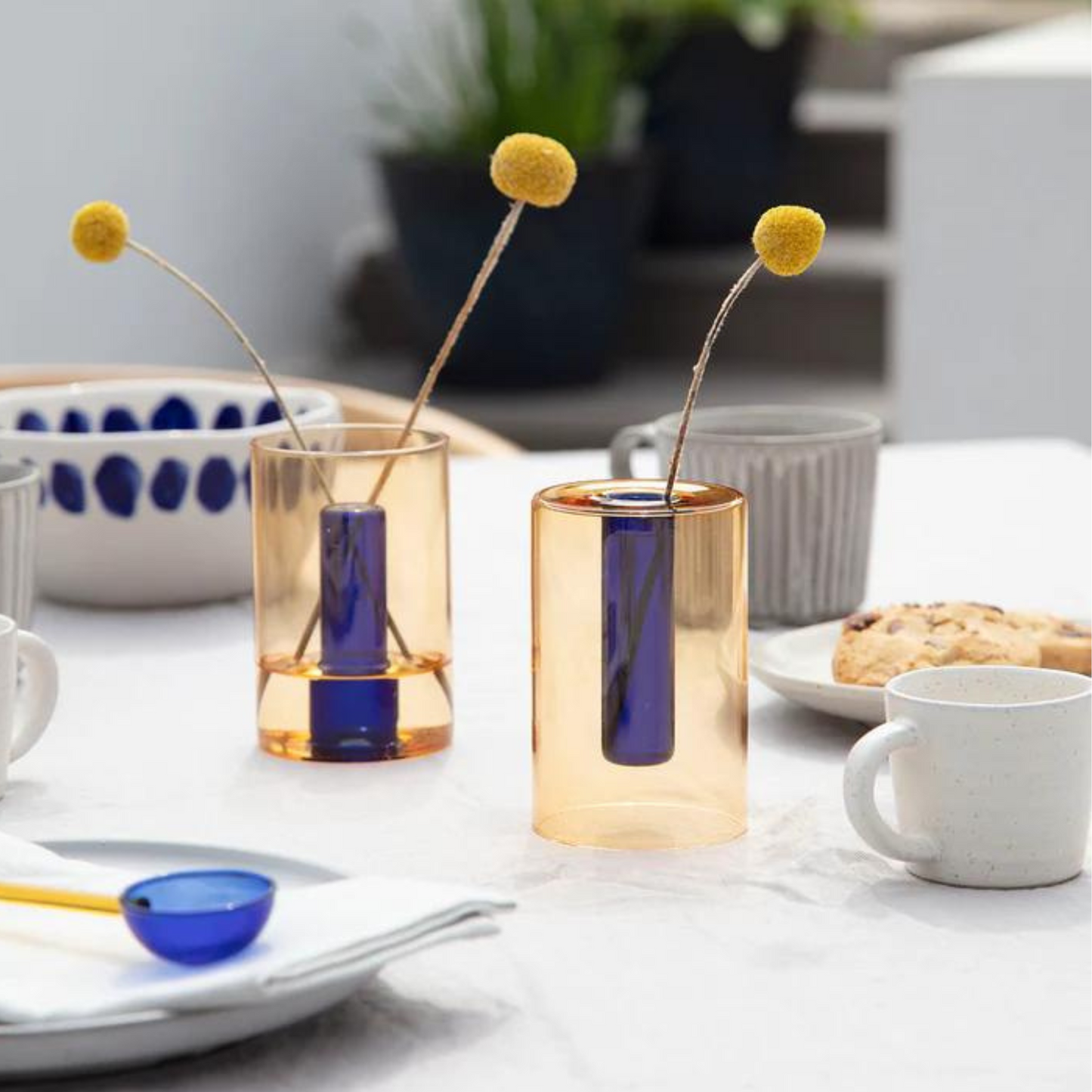 Load image into Gallery viewer, reversible glass vase in cobalt and peach on a table setting with mugs, bowls and spoons.
