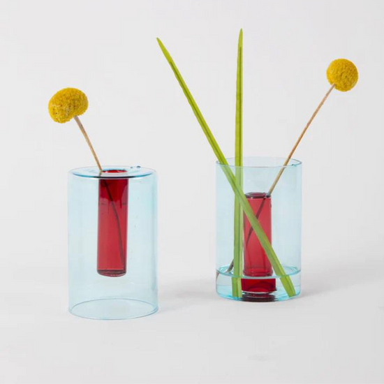 reversible glass vase in red and blue with flower stems.