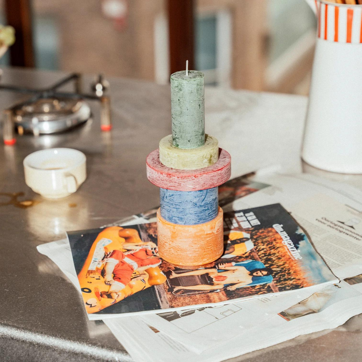 stack candle of 5 different colour components sitting on a magazine on a coffee table.