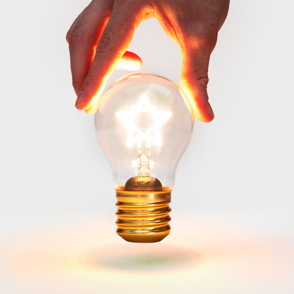 
                  
                    A hand holding a lit up cordless star shaped lightbulb
                  
                